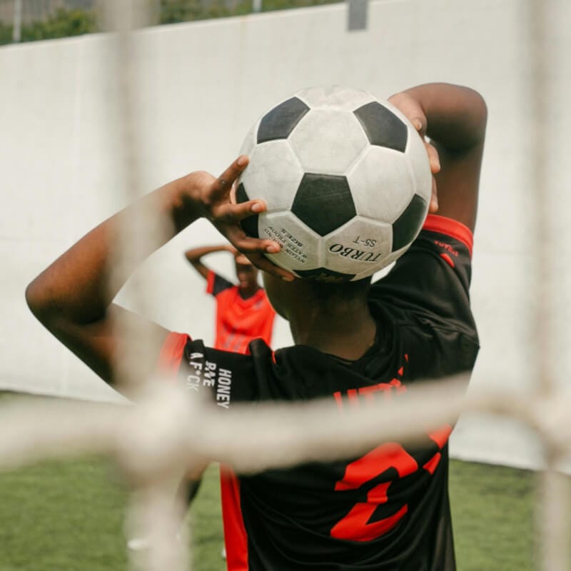 Youth soccer player holding soccer ball for throw-in during football match